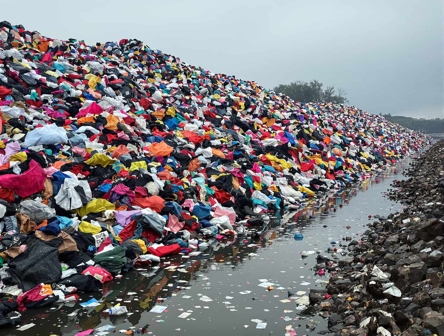 A vast pile of discarded clothing in a textile landfill